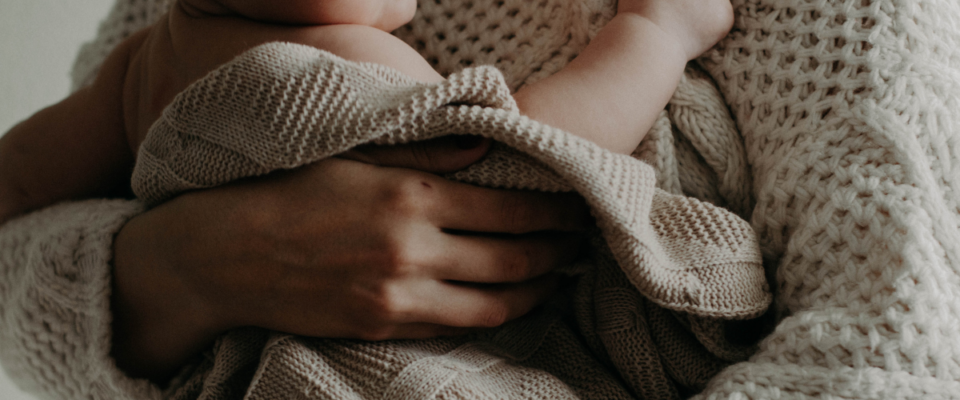 Frau mit Baby auf dem Arm, die über Herausforderungen im ersten Babyjahr nachdenkt.