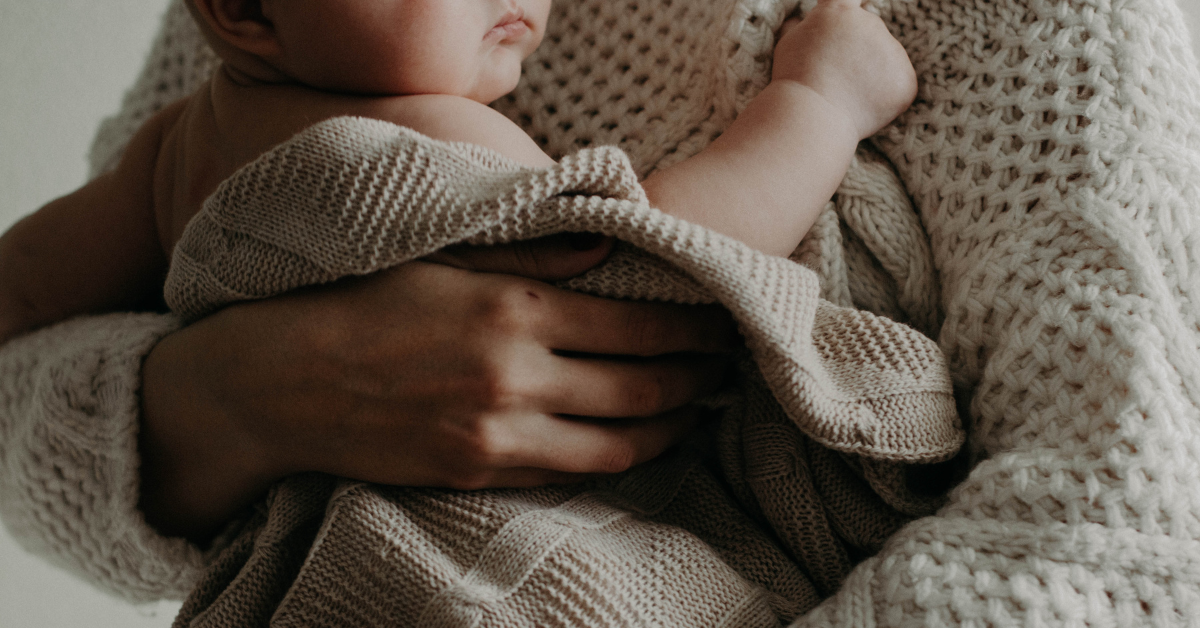 Frau mit Baby auf dem Arm, die über Herausforderungen im ersten Babyjahr nachdenkt.